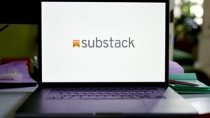 an opened laptop on a table with the Substack logo and name displayed on the laptop’s white screen.