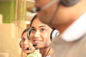 Close-up of smiling customer service representatives wearing headsets in an office setting