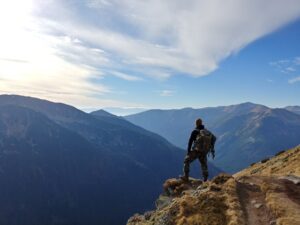man standing on mountain under blue sky