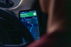 A smartphone mounted in a car displaying a GPS navigation app with a route on a map