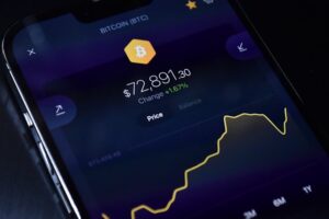 Close-up of a smartphone screen displaying a Bitcoin price chart at $72,891.30