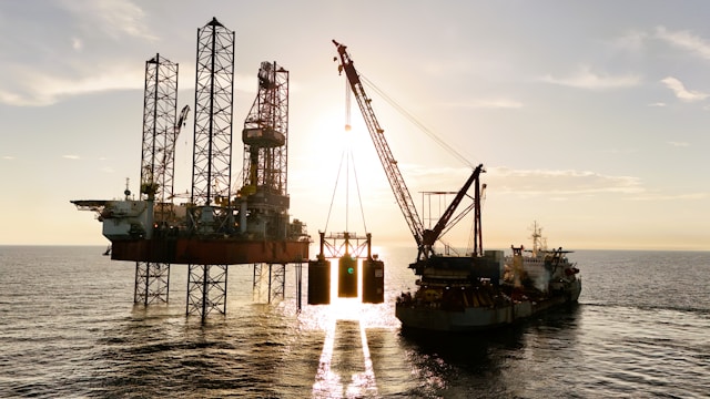 an oil rig being serviced by a supply ship